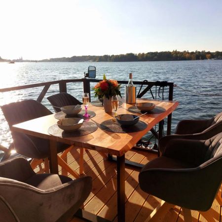 Bugterasse des Hausbootes mit gedecktem Tisch und Stühlen laden zum Essen und Verweilen während des Urlaubs ein.